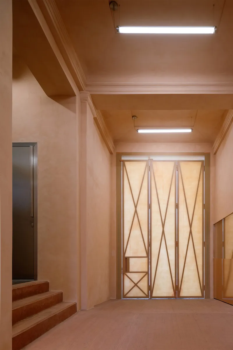 Entry hall with coffered plywood ceiling and geometric folding doors under fluorescent lighting