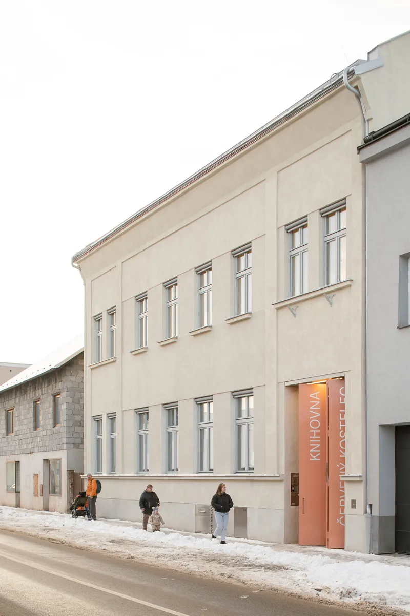 Two-story street elevation with regularly spaced windows and orange banners, pedestrians on snowy sidewalk
