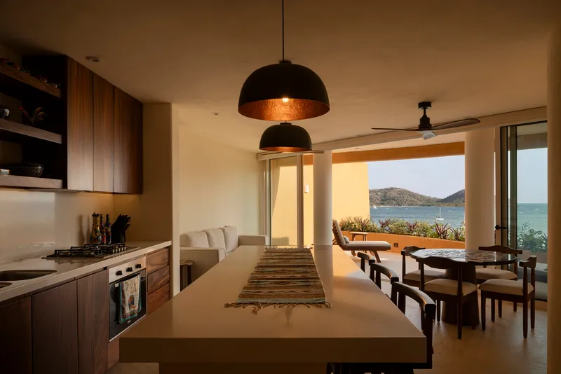 Open kitchen and dining area with pendant lights looking through to the ocean terrace