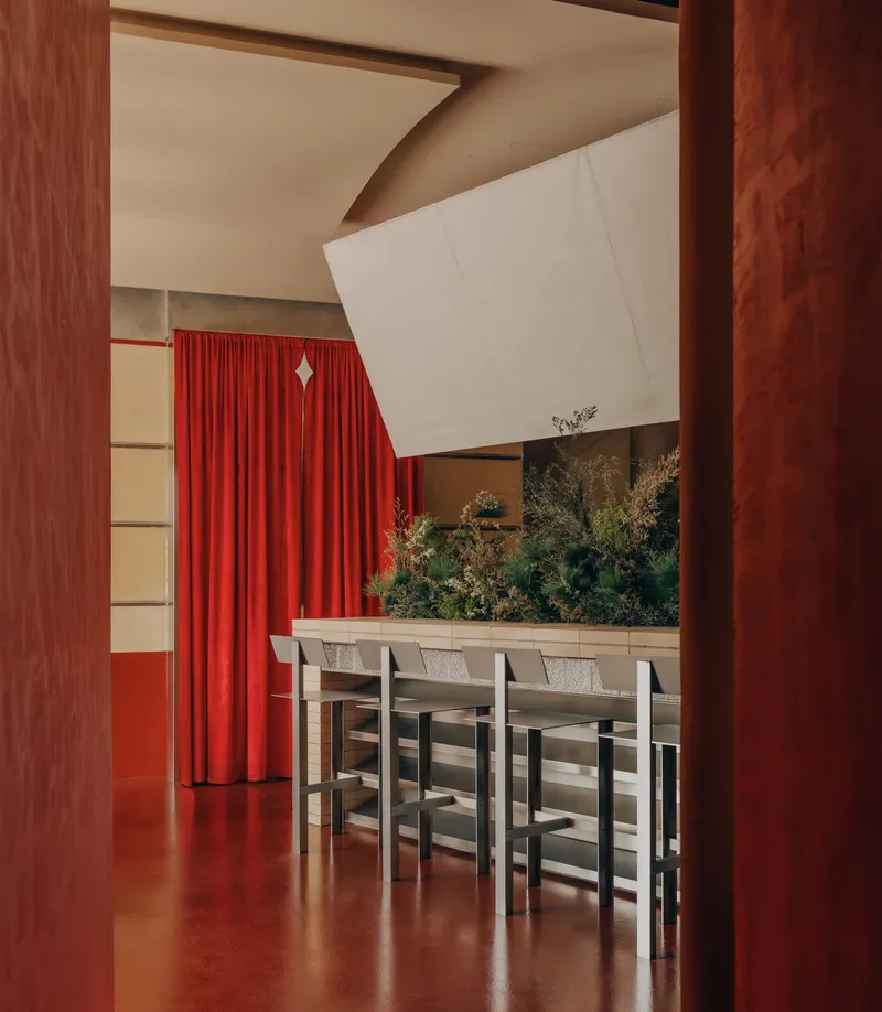 Dining area framed by timber columns with red epoxy floor and angled white ceiling volume above