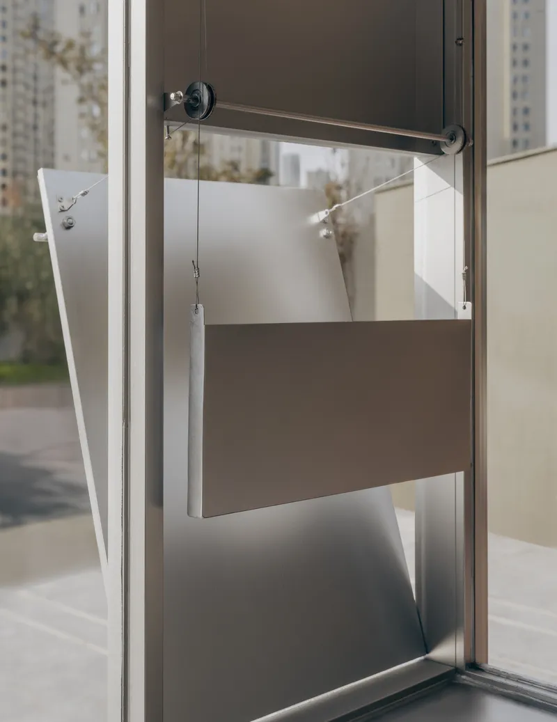 Pivoting window panel with exposed counterweight system and metal rod mechanism in white frame