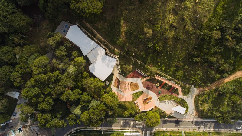 Overhead view of the angular roof and interconnected playground surfaces surrounded by dense tree canopy