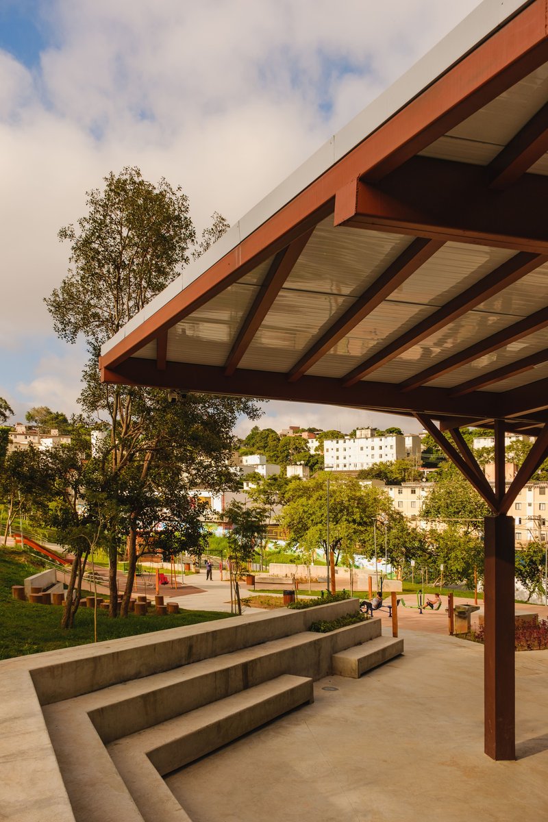 Cantilevered roof canopy with exposed timber structure above concrete steps and playground beyond