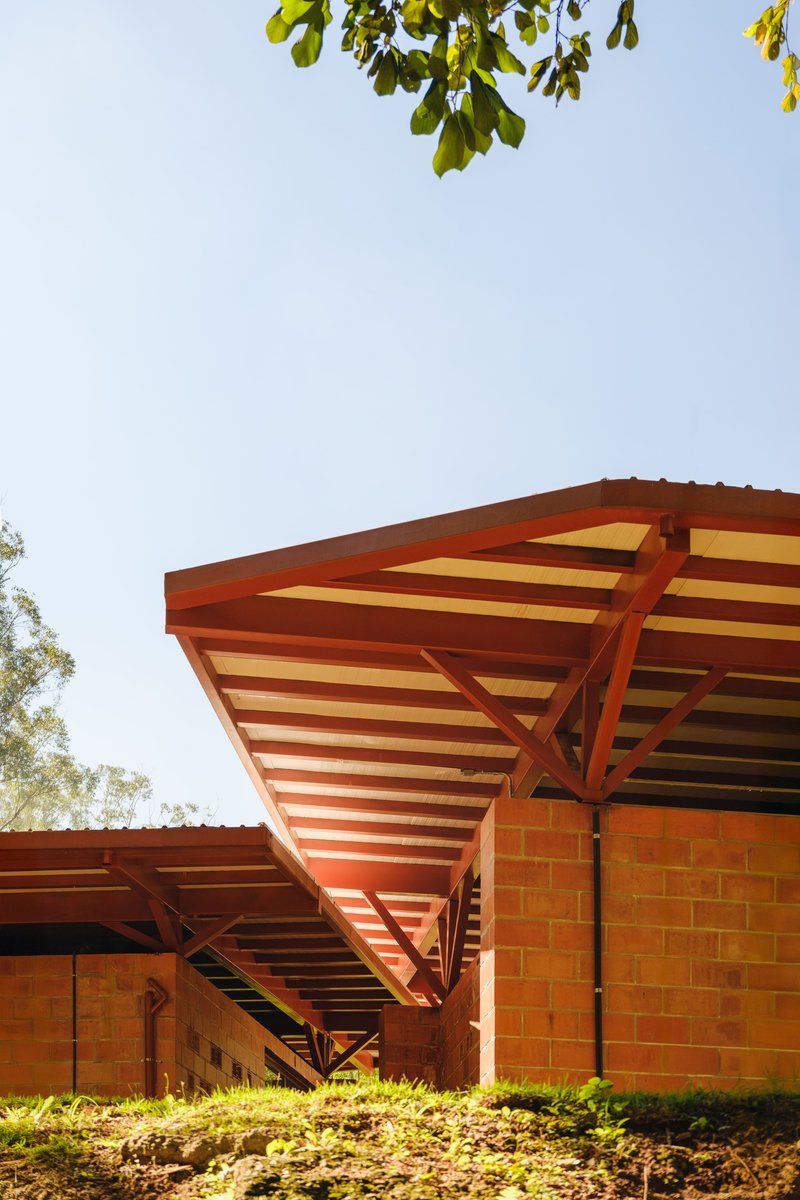 Diagonal timber bracing supporting the cantilevered canopy above red brick wall in sunlight
