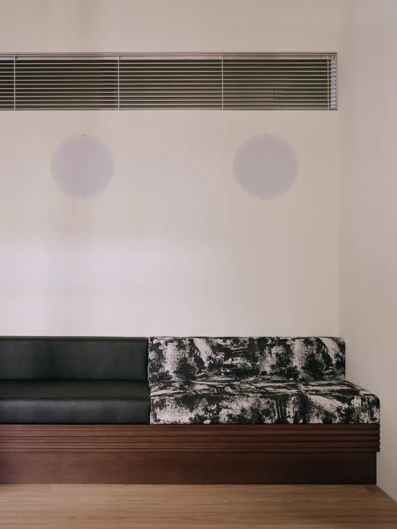 Bench detail showing the printed fabric end and two acoustic discs on the wall