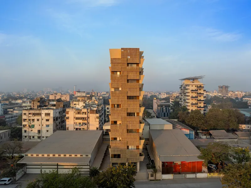 Stacked brick tower rising above a dense urban neighborhood at dusk