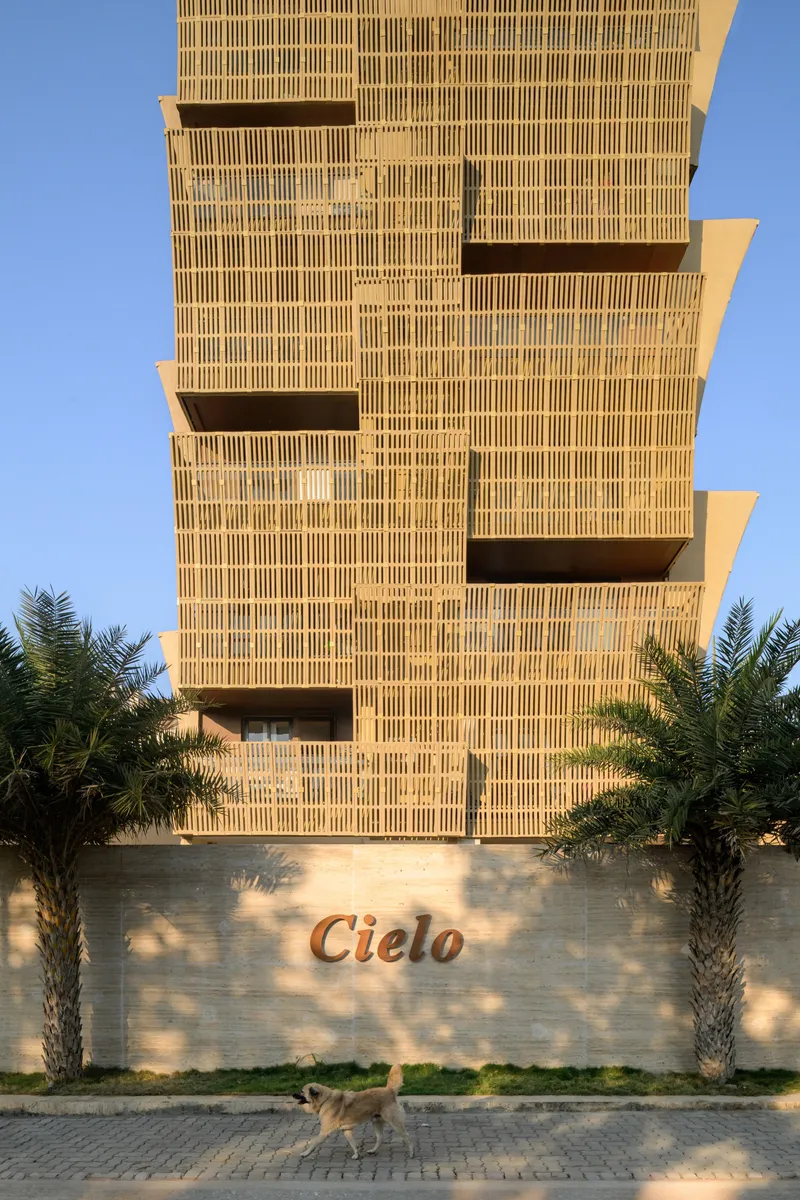 Tower entrance with vertical brick screen above a low boundary wall and flanking palm trees