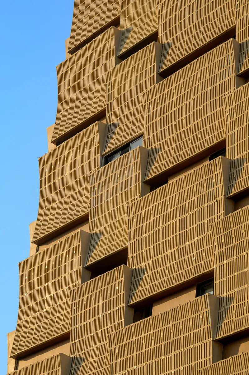 Close-up of the staggered brick facade showing recessed balconies and deep shadows
