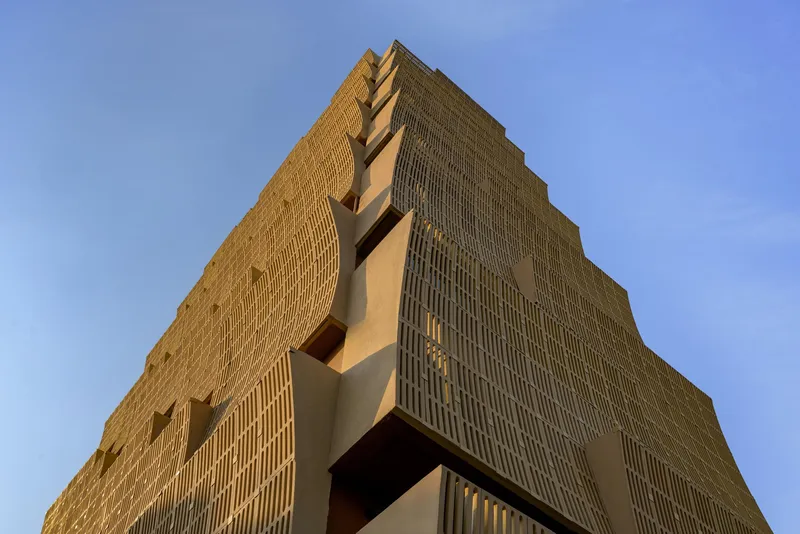 Corner detail of the stepped brick facade showing projecting volumes and vertical ribbed texture in afternoon light