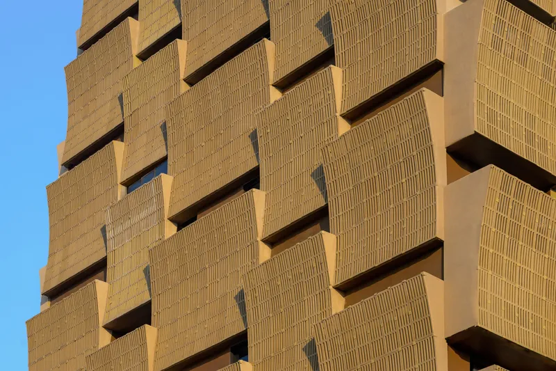 Close-up of the ribbed brick facade showing deep horizontal balconies with vertical slot windows