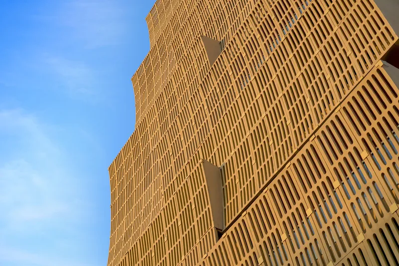 Facade detail showing vertical slats and triangular recesses in warm afternoon light