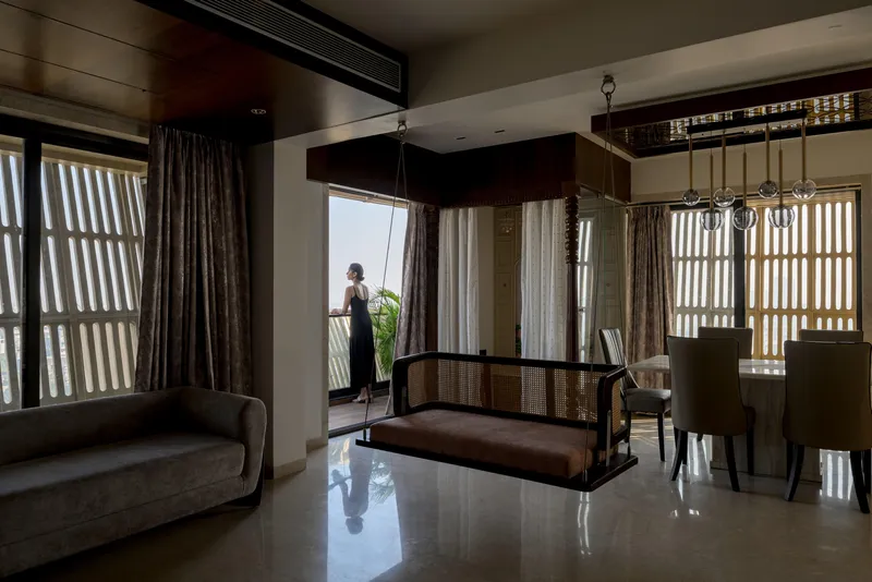 Living space with cane furniture and vertical timber screens framing a figure at the balcony