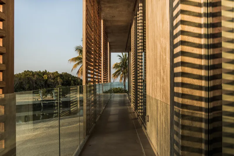 Covered walkway with slatted timber screens casting striped shadows in warm afternoon light