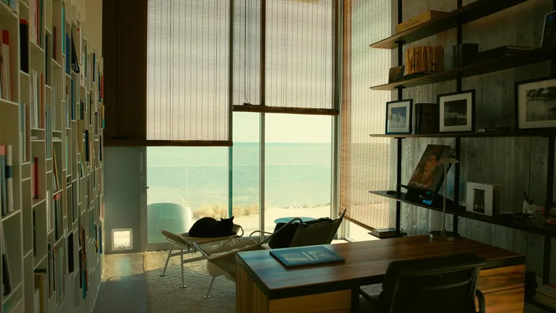 Interior workspace with timber desk and floor-to-ceiling window overlooking the ocean through translucent shades