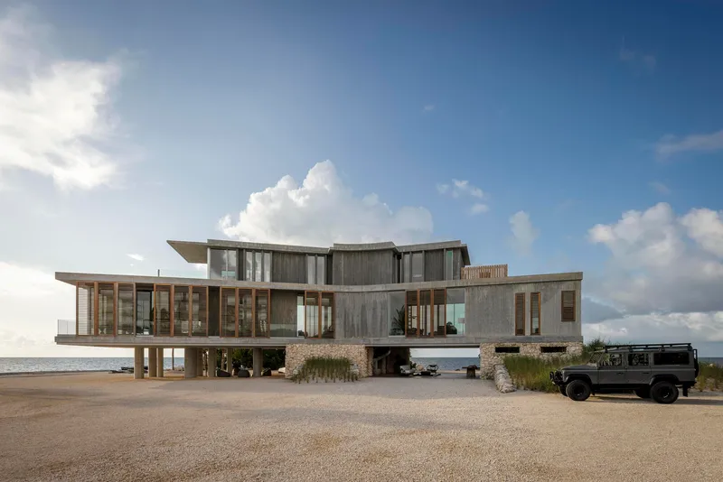 Beach approach showing the stacked concrete and timber volumes with central carport and parked vehicle