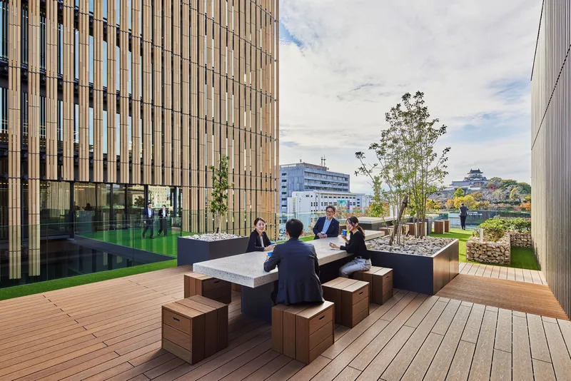 Rooftop terrace with timber decking and seating arrangement overlooking distant temple and trees