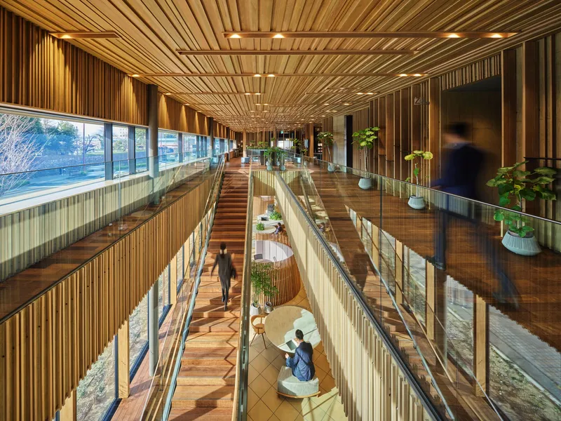 Multi-level interior atrium with timber slat ceiling, wood flooring, and glass railings with potted plants