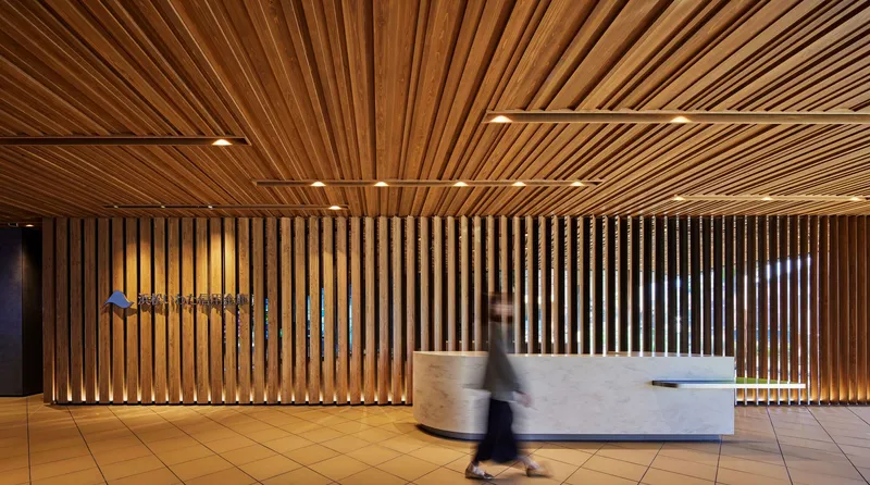 Lobby reception desk with vertical timber slat wall and radiating slatted ceiling with a figure in motion