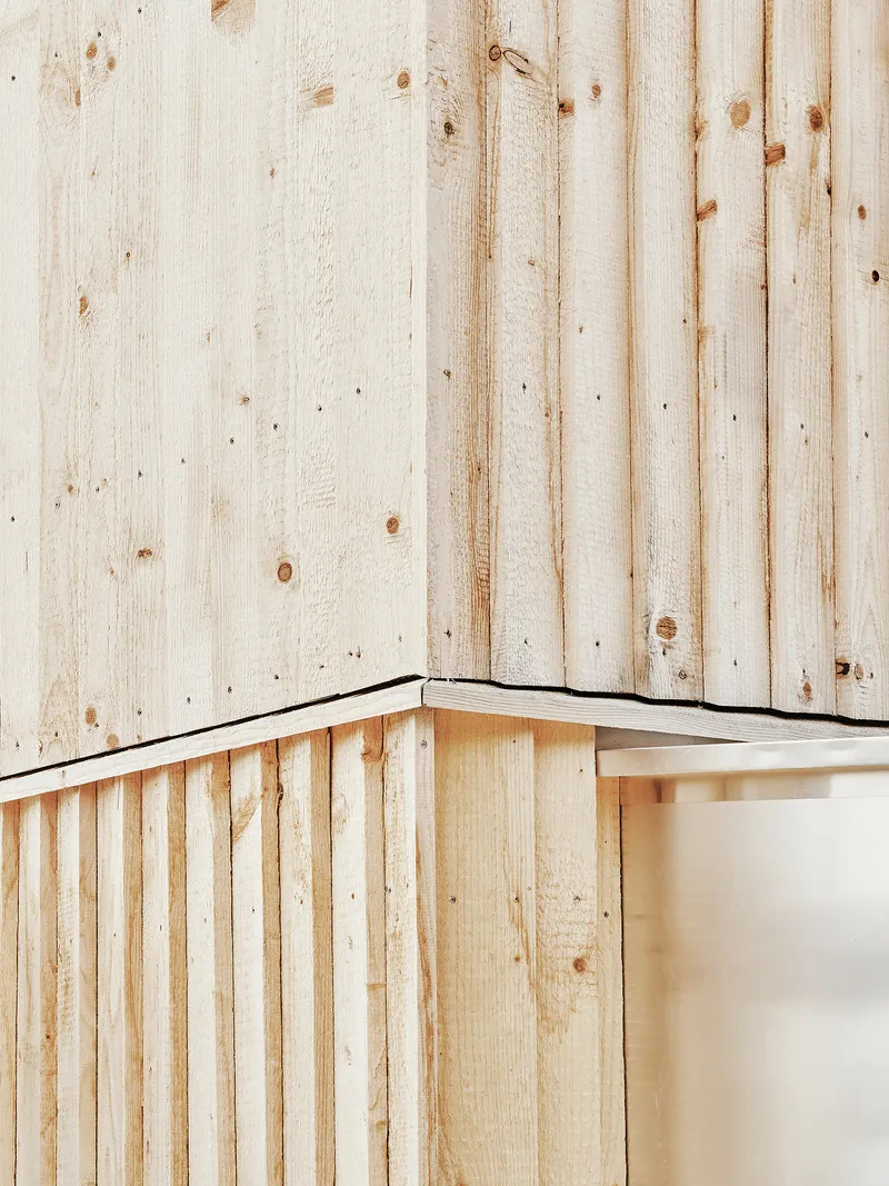 Close-up of an external corner showing two layers of vertical timber boarding