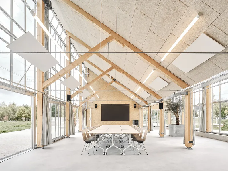 Central event space with a long table, screen and timber roof structure exposed