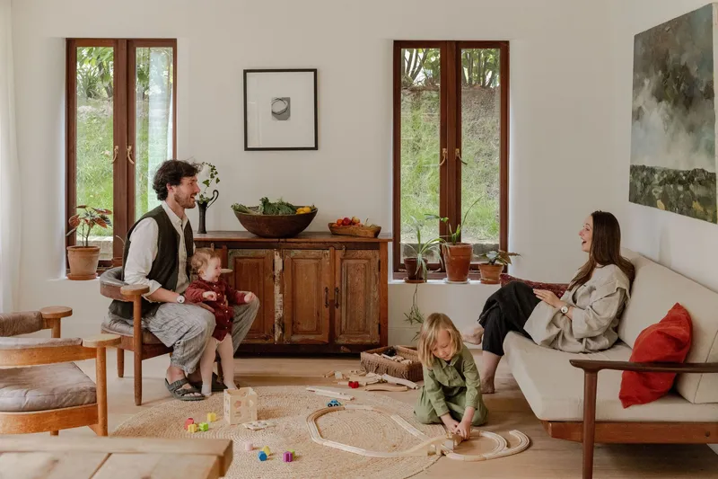 Living room with twin timber-framed doors flanking a wooden sideboard as a family gathers on the floor