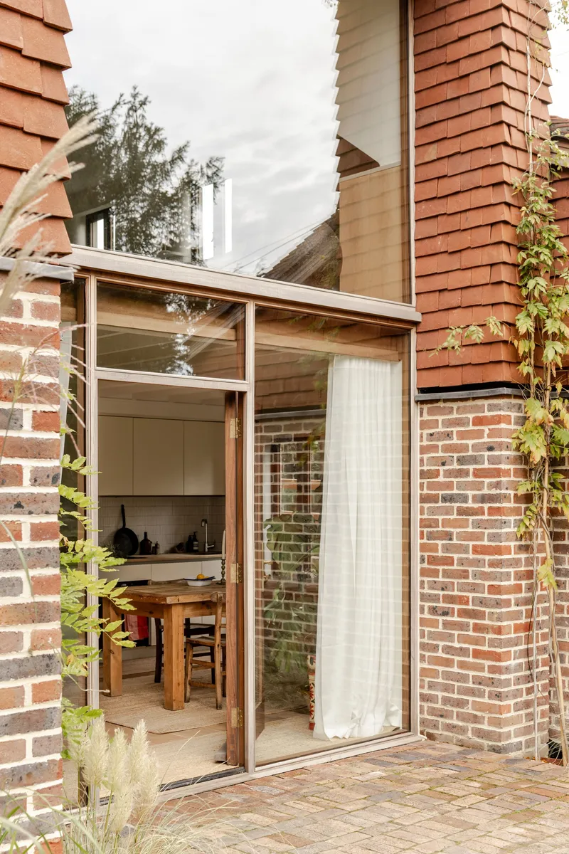 Corner courtyard with sliding glass doors opening to a dining area between brick walls