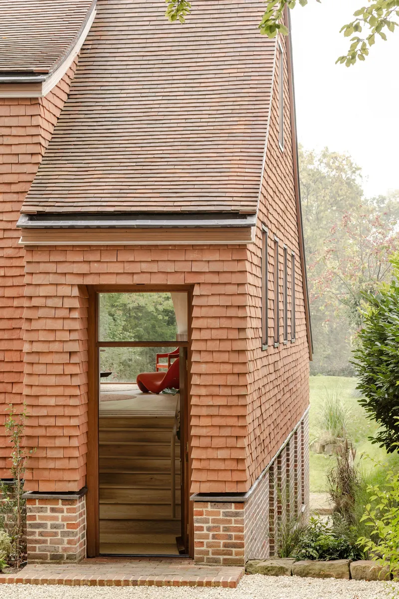 Entrance detail showing glazed door on brick plinth beneath horizontally-tiled upper volumes