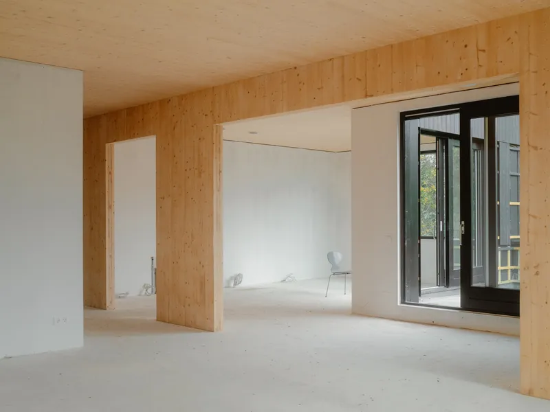Unfurnished interior room with exposed plywood walls and ceiling opening to a small balcony