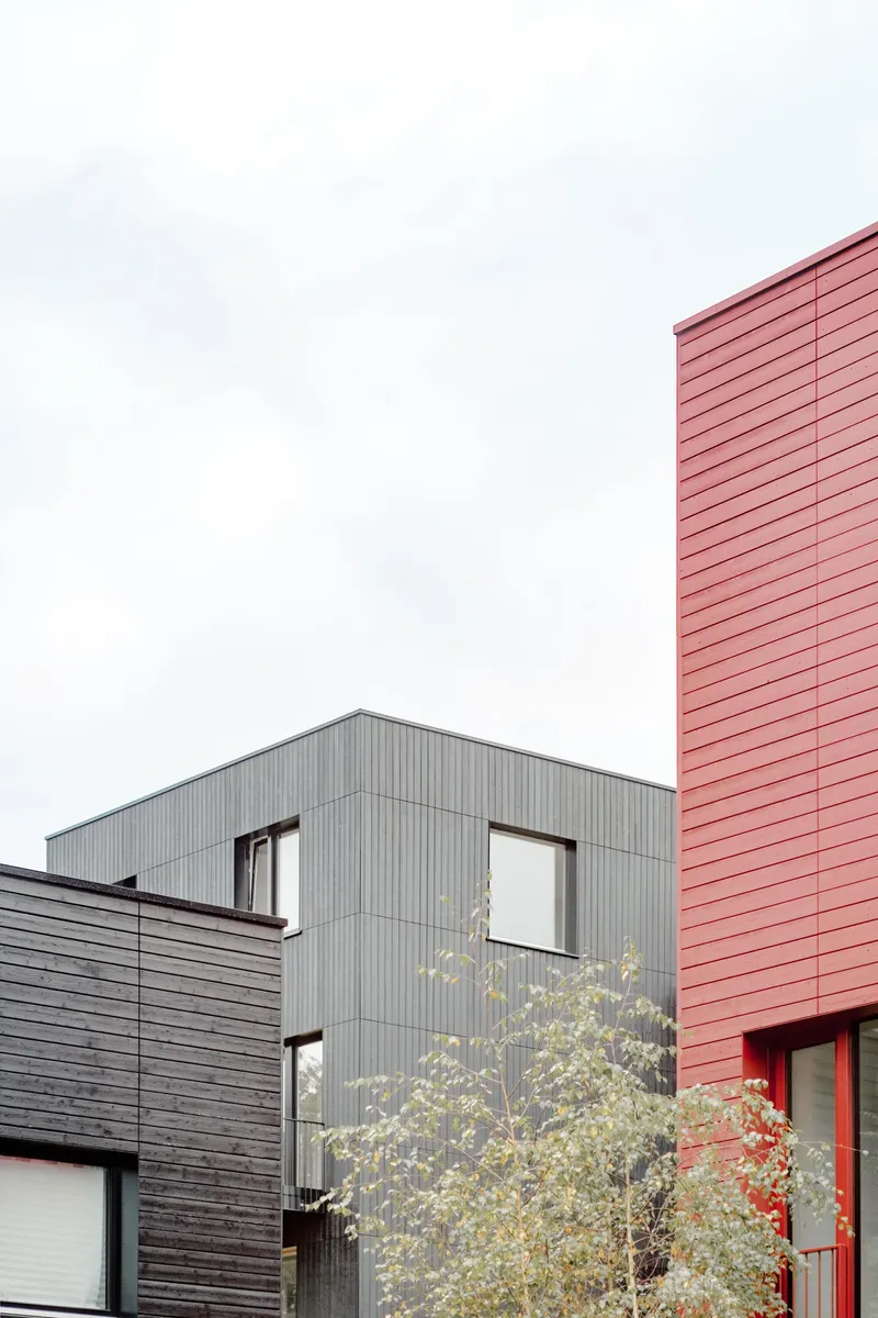 Clustered volumes with grey corrugated metal and pink panel cladding under an overcast sky