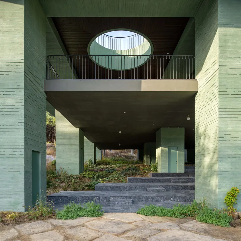Covered terrace with oval skylight framed by green tiled columns and a dark wood ceiling