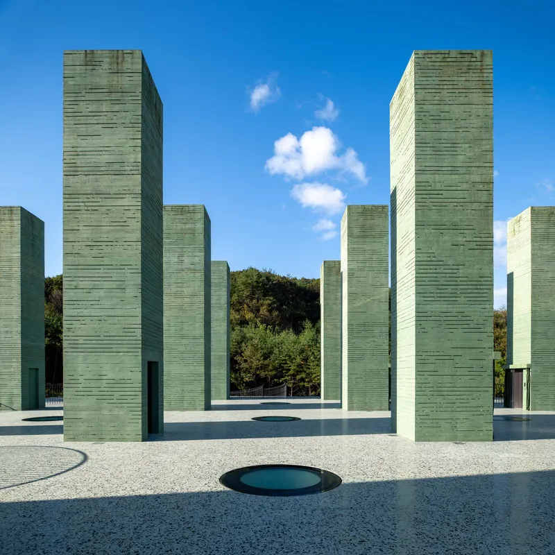 Forest of green concrete towers arranged on a terrazzo roof beneath scattered white clouds