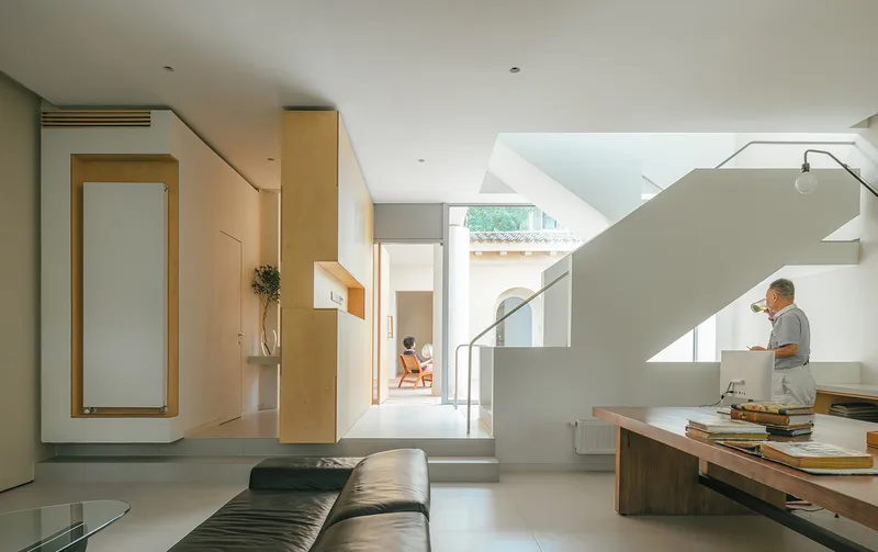 Open living space with timber millwork and white staircase flooded with afternoon sunlight