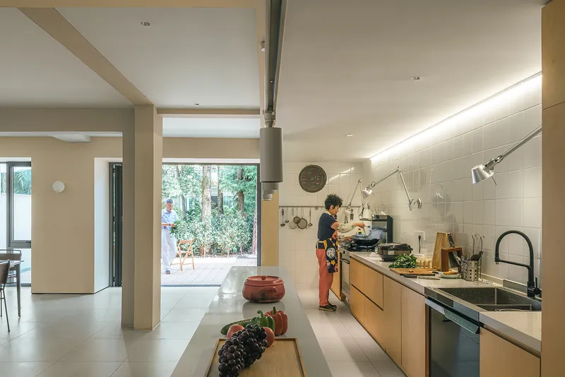 Open kitchen with timber cabinetry and white tile backsplash as someone prepares food