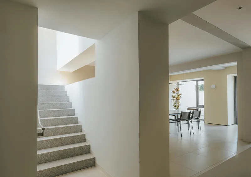 Terrazzo staircase framed by white columns with dining area visible beyond