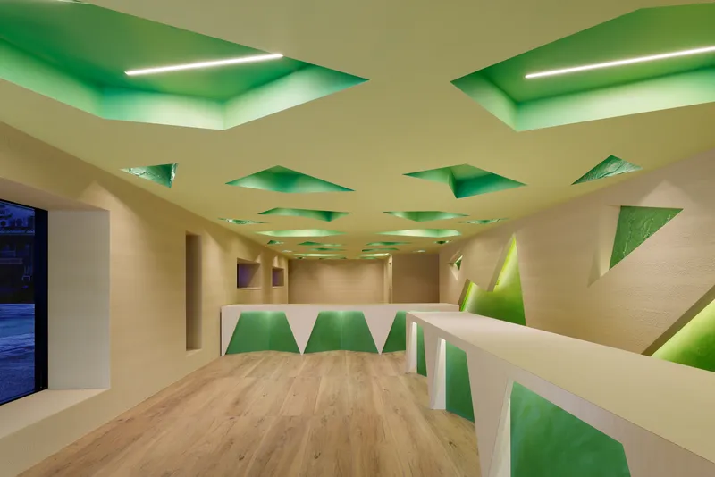 Wide office view with the patterned ceiling, faceted counters and a window at the far end