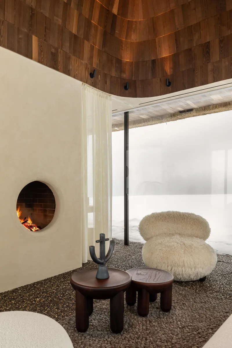 Interior corner with circular fireplace opening and curved wood-clad ceiling above gravel floor