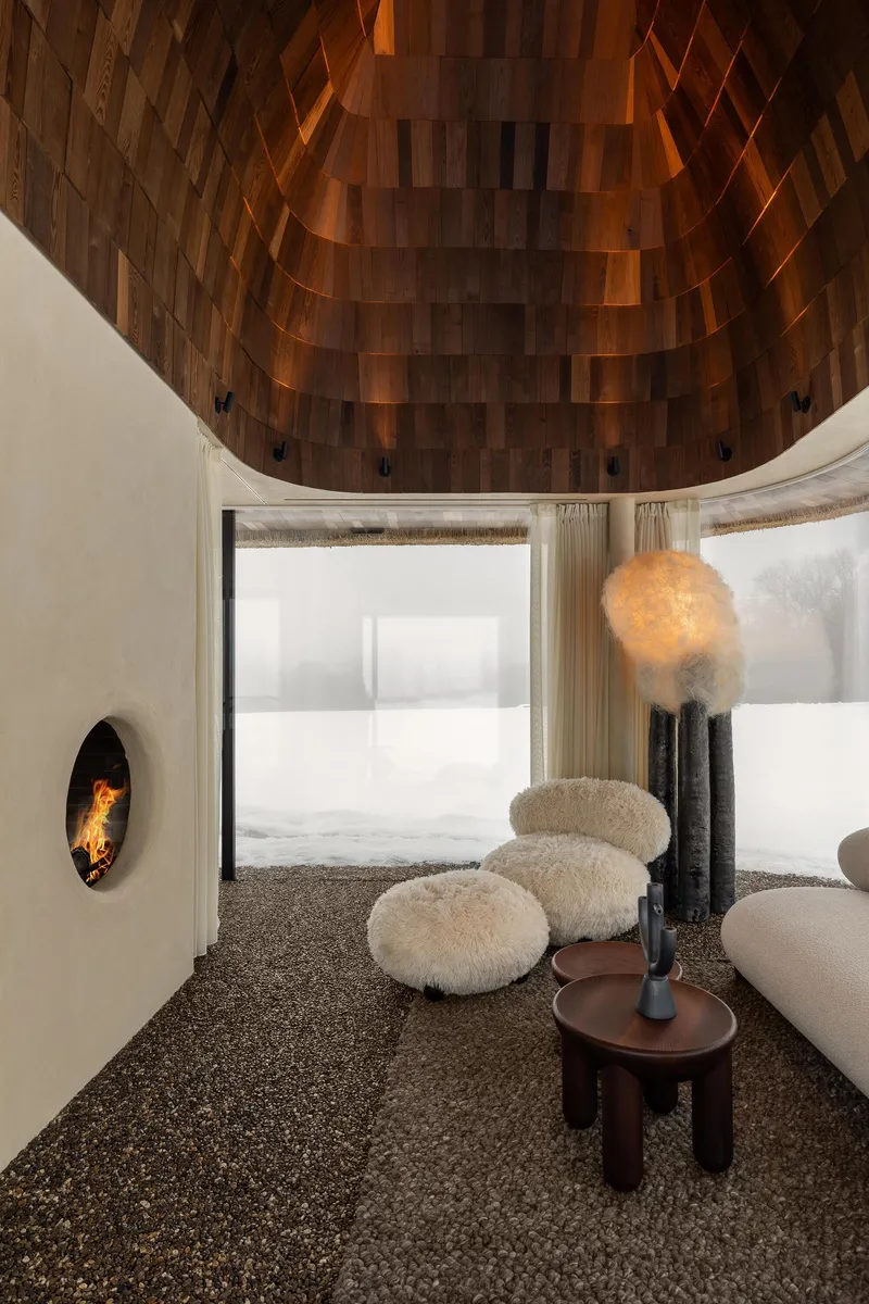 Upward view of the domed wood ceiling with pendant light and fireplace in the curved white wall
