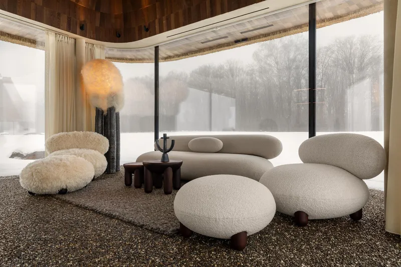 Seating area with curved glazing framing bare winter trees in the snowy landscape beyond