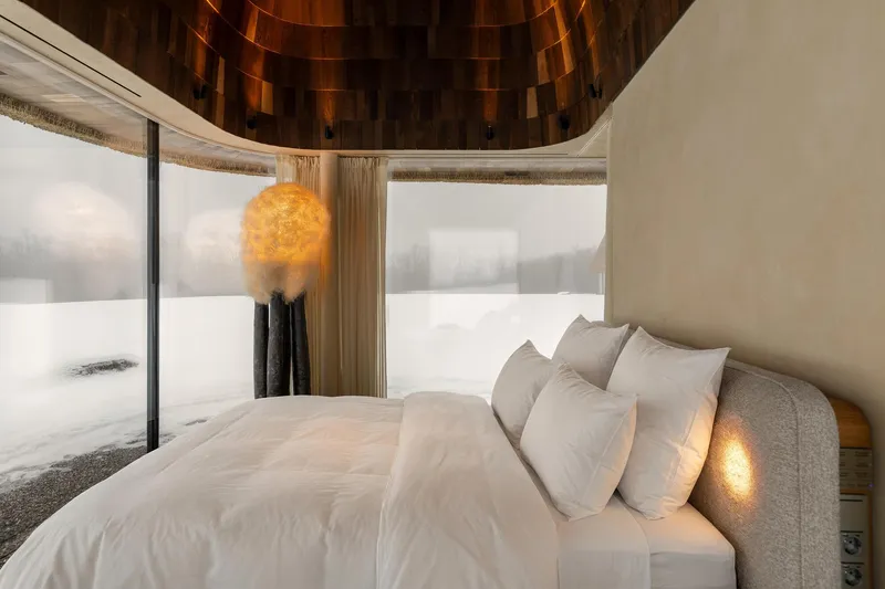 Sleeping area with continuous curved windows framing views of snow-covered terrain in winter
