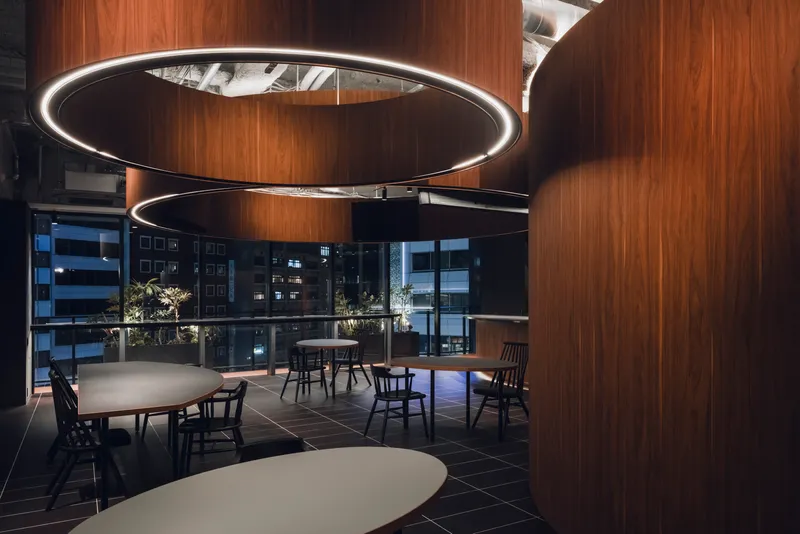 Evening view of dining area showing circular LED pendants and city lights through floor-to-ceiling glazing