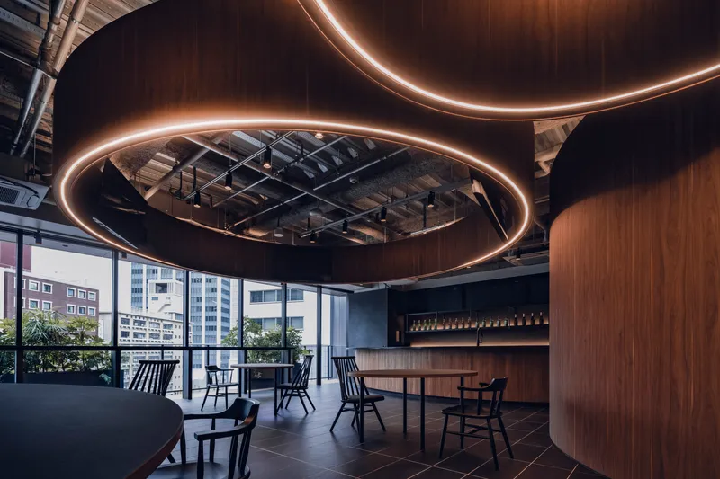 View toward floor-to-ceiling windows showing circular lighting elements framing the exposed structural ceiling above