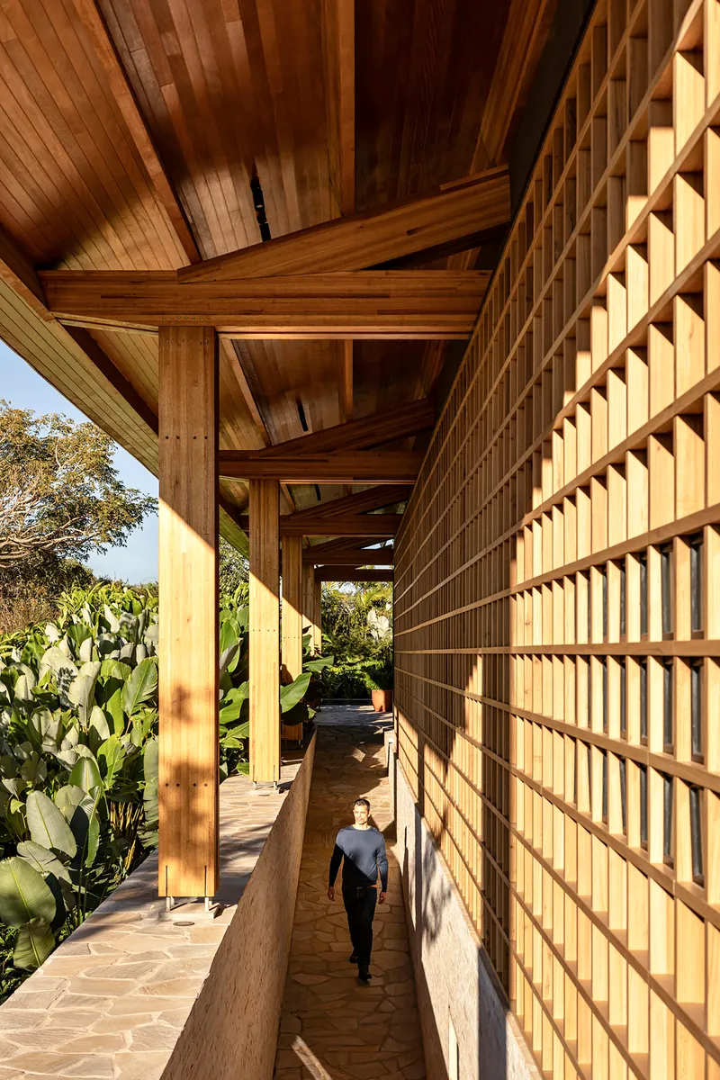 Exterior corridor with timber lattice screen and figure walking in afternoon shadow
