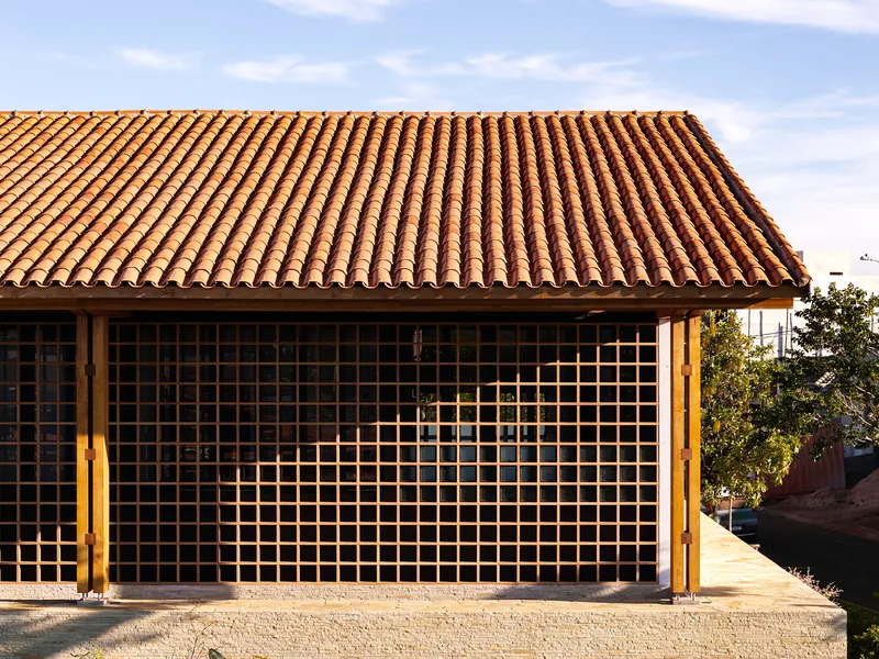 Facade with timber grid screen beneath a clay tile roof under overcast sky