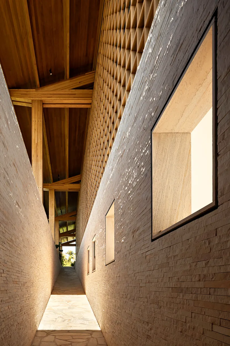 Narrow passage between pale brick walls with exposed timber roof structure at dusk