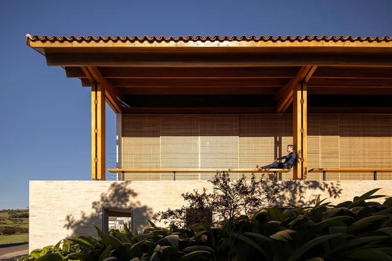 Upper terrace with perforated brick screen panels and timber roof soffit lit at dusk