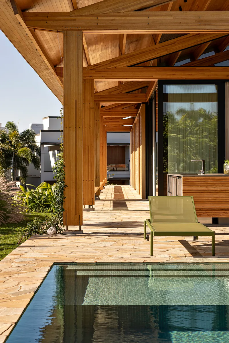 Exterior terrace with small pool, timber structure and green lounge chair overlooking lawn and palms