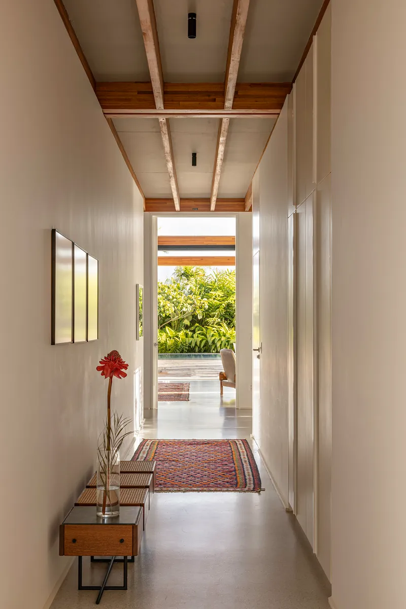 Hallway with timber and white panel ceiling leading to a terrace with tropical foliage beyond