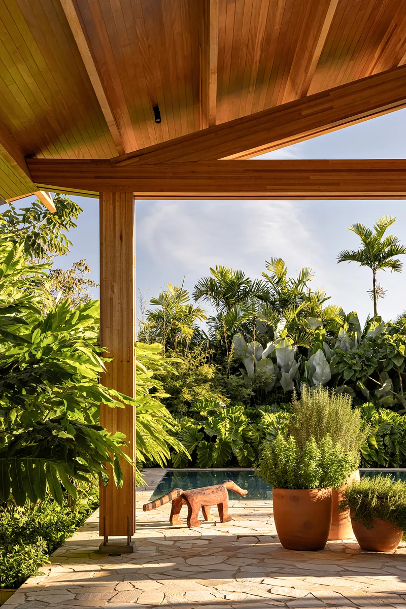 Corner window framing a terrace with planted pots and tropical palms under an overcast sky