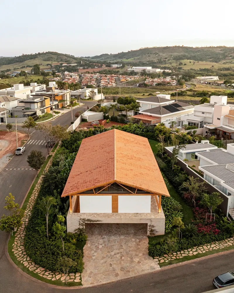 Aerial view of the curved timber roof sheltering a stone terrace within a residential neighborhood