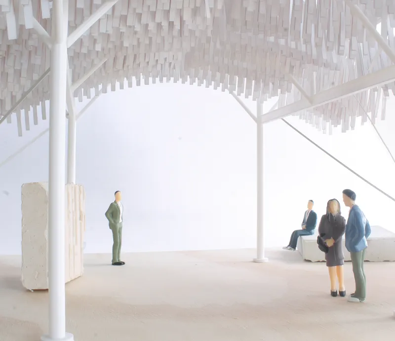Interior view of the model showing white structural columns, vertical hanging elements, and grouped miniature figures